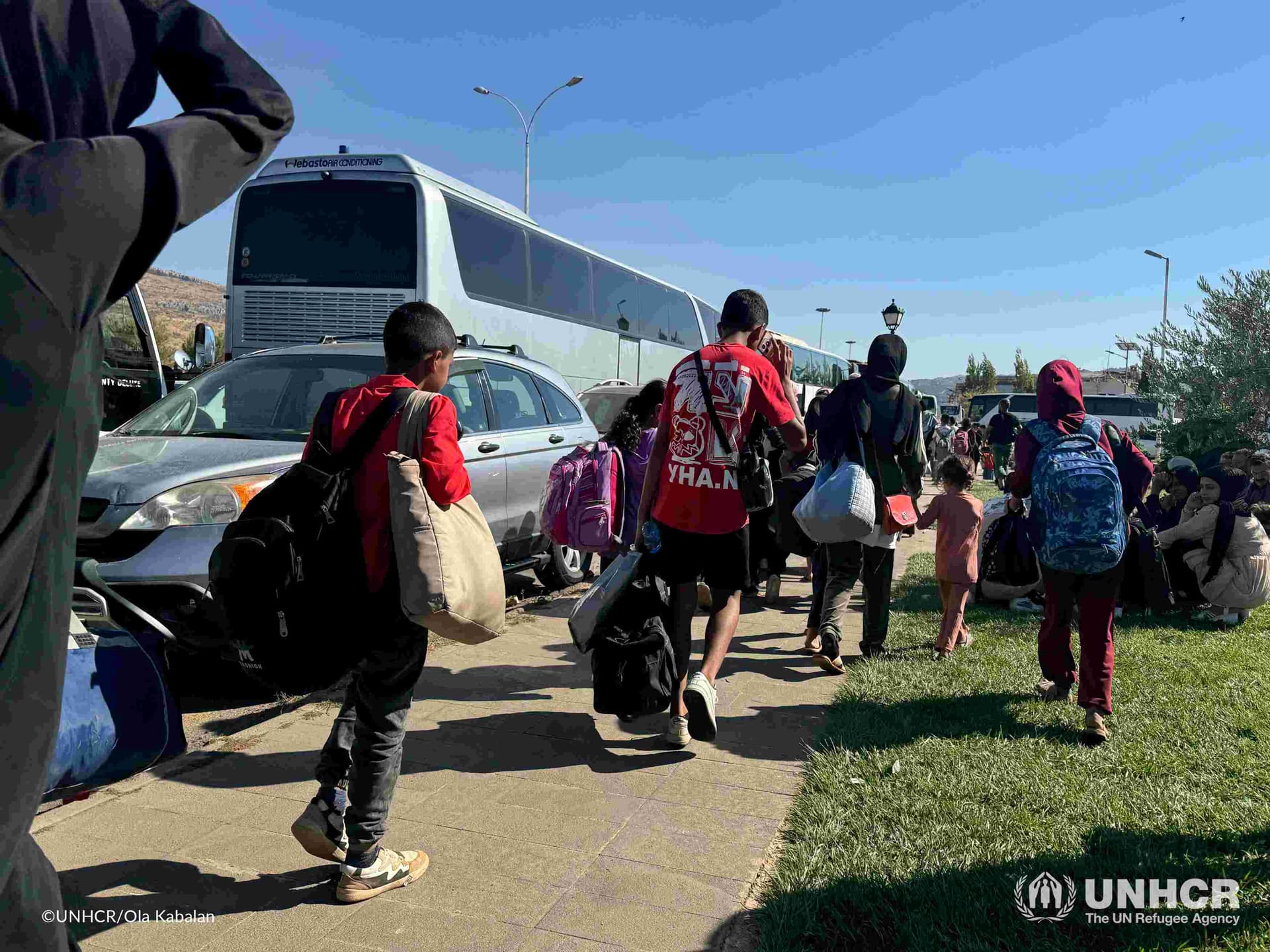Sekelompok anak-anak berjalan kaki di tengah antrean kendaraan dari Lebanon yang mengantre di perbatasan untuk mengungsi ke Suriah. Foto: UNHCR