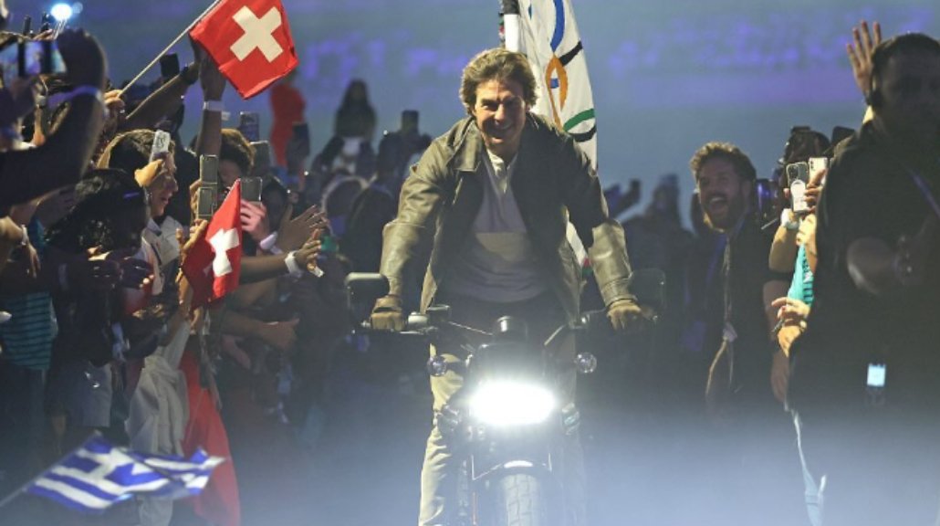 Aktor Hollywood itu membawa bendera dengan sepeda motor.&nbsp;(Foto: Instagram @olympics)