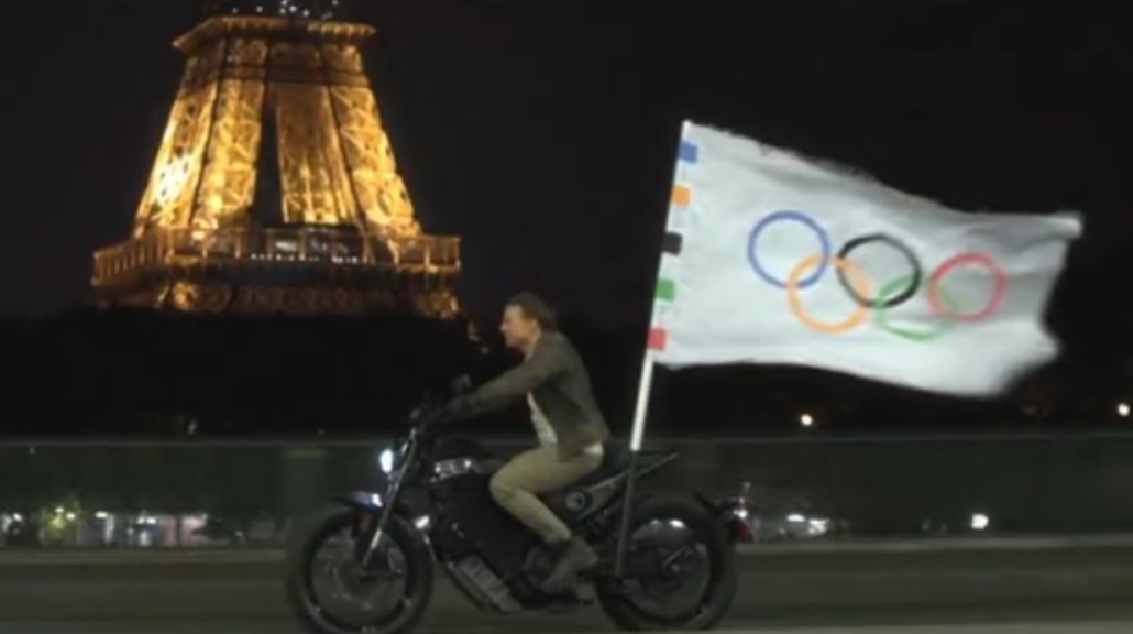 Dia menyusuri jalan-jalan Paris dengan sepeda motor dan terlihat bendera Olimpiade diikat di belakang kendaraan itu.&nbsp;(Foto: Instagram @olympics)