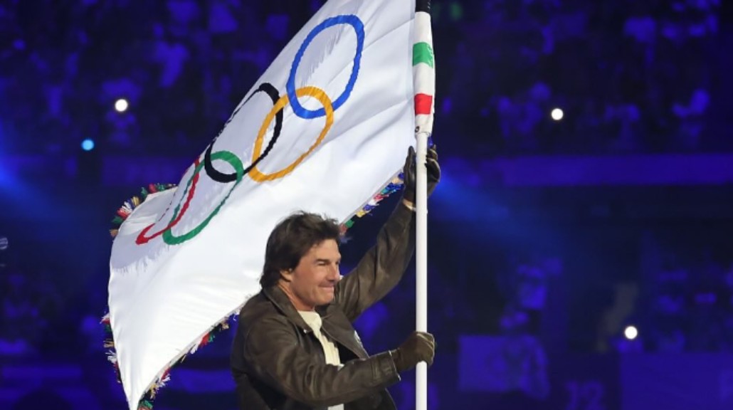 Tom Cruise membawa bendera Olimpiade. (Foto: Instagram @olympics)